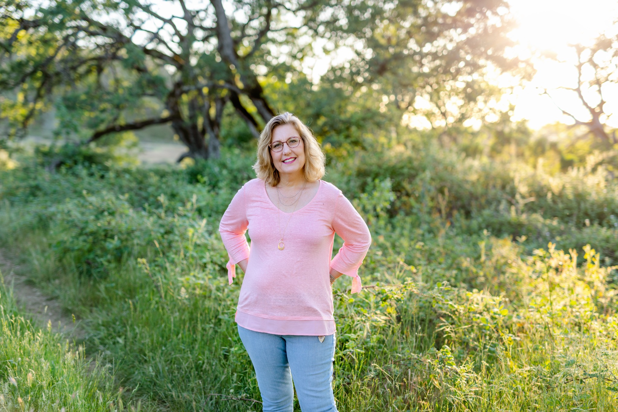 Jenny Wells standing in a sunlit woodland meadow